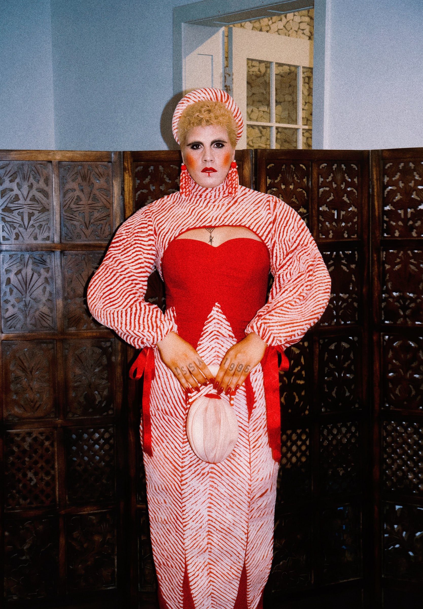Full-length personal record: red dress, striped panels and oval accessory.